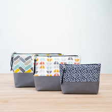 Load image into Gallery viewer, Three patterned pouches with gray bases on a wooden surface Cecily Zipper Pouch Sewing Pattern PDF