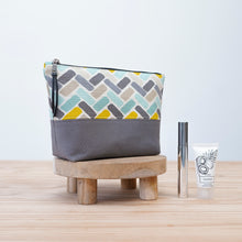 Load image into Gallery viewer, Patterned pouch on a wooden stool with skincare products on a light Cecily Zipper Pouch Sewing Pattern PDF background