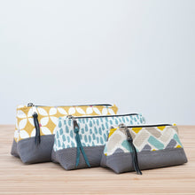 Load image into Gallery viewer, Three fabric pouches with different patterns on a wooden surface and light blue background Nora Zipper Pouch Pattern PDF