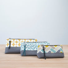 Load image into Gallery viewer, Three fabric pouches with different patterns on a wooden surface and light blue background Nora Zipper Pouch Pattern PDF