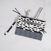 Load image into Gallery viewer, Black and white patterned pouch with cosmetic items on a light gray surface Ria Wristlet Sewing Pattern PDF