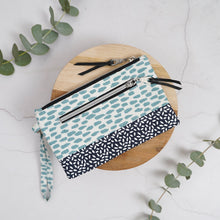 Load image into Gallery viewer, Two fabric pouches with zipper on a wooden board with eucalyptus leaves. Ria Wristlet Sewing Pattern PDF