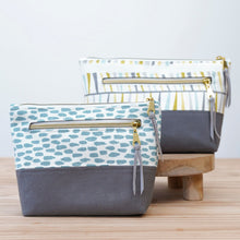 Load image into Gallery viewer, Two fabric bags with gold zippers on a wooden stand against a light background. Ayla Zipper Pouch Sewing Pattern PDF
