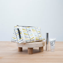 Load image into Gallery viewer, Patterned toiletry bag on a wooden stool with skincare products on a light background Iris Zipper Pouch Pattern PDF
