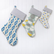 Load image into Gallery viewer, Three patterned stockings hanging on a white wooden surface Joelle Christmas Stocking Sewing Pattern PDF
