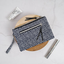 Load image into Gallery viewer, Black and white patterned pouch on a marble surface with a pen and bottle. Lena Wristlet Sewing Pattern PDF
