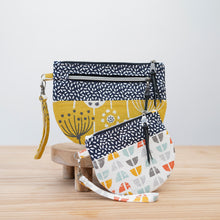 Load image into Gallery viewer, Three patterned handbags on a wooden surface with a light gray background Lexi Wristlet Sewing Pattern PDF
