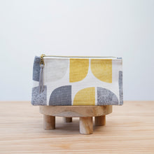 Load image into Gallery viewer, Fabric pouch with geometric pattern on a wooden stand against a light  Tasnim Pencil Case Sewing Pattern PDFbackground
